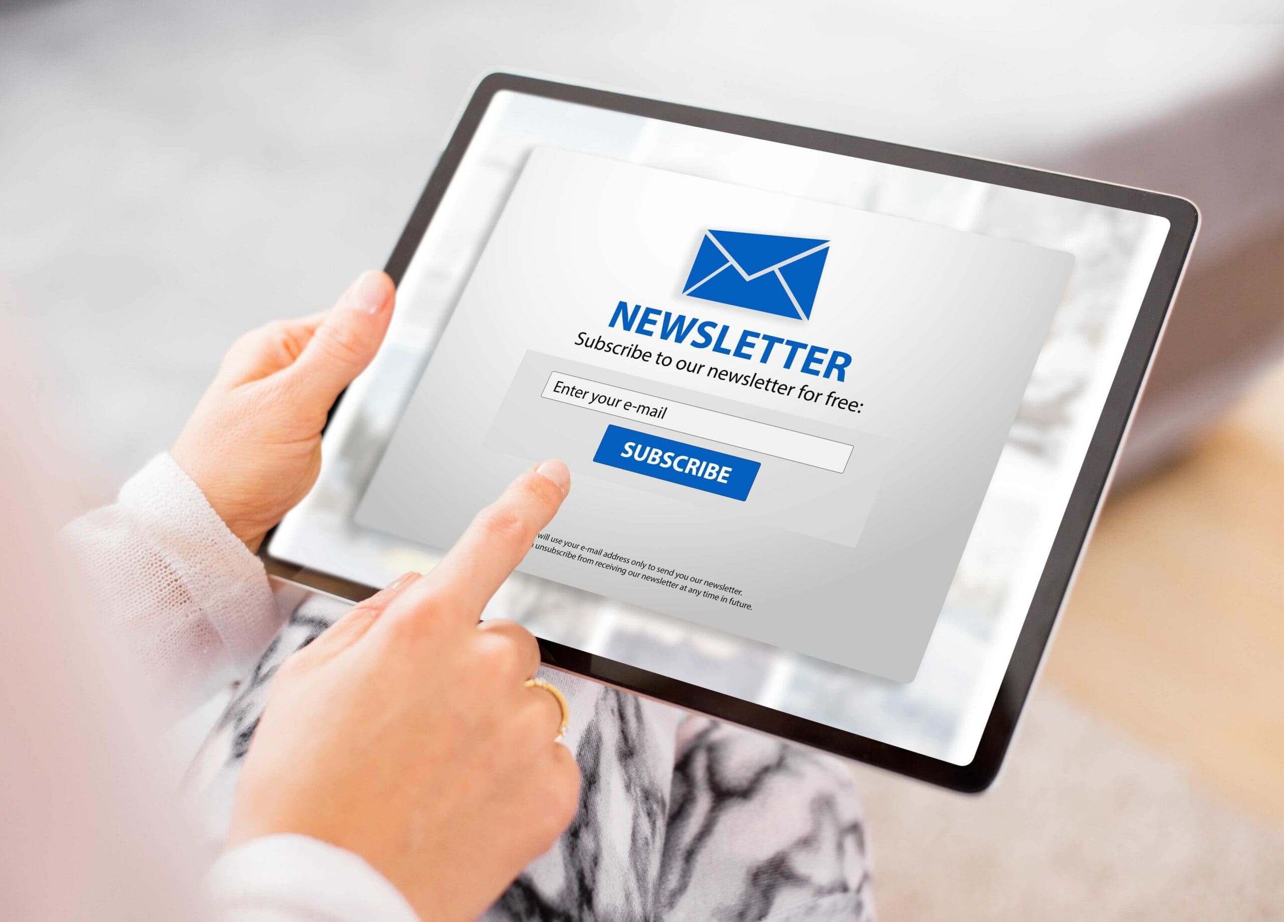 person holding a tablet pointed to a newsletter subscription button.
