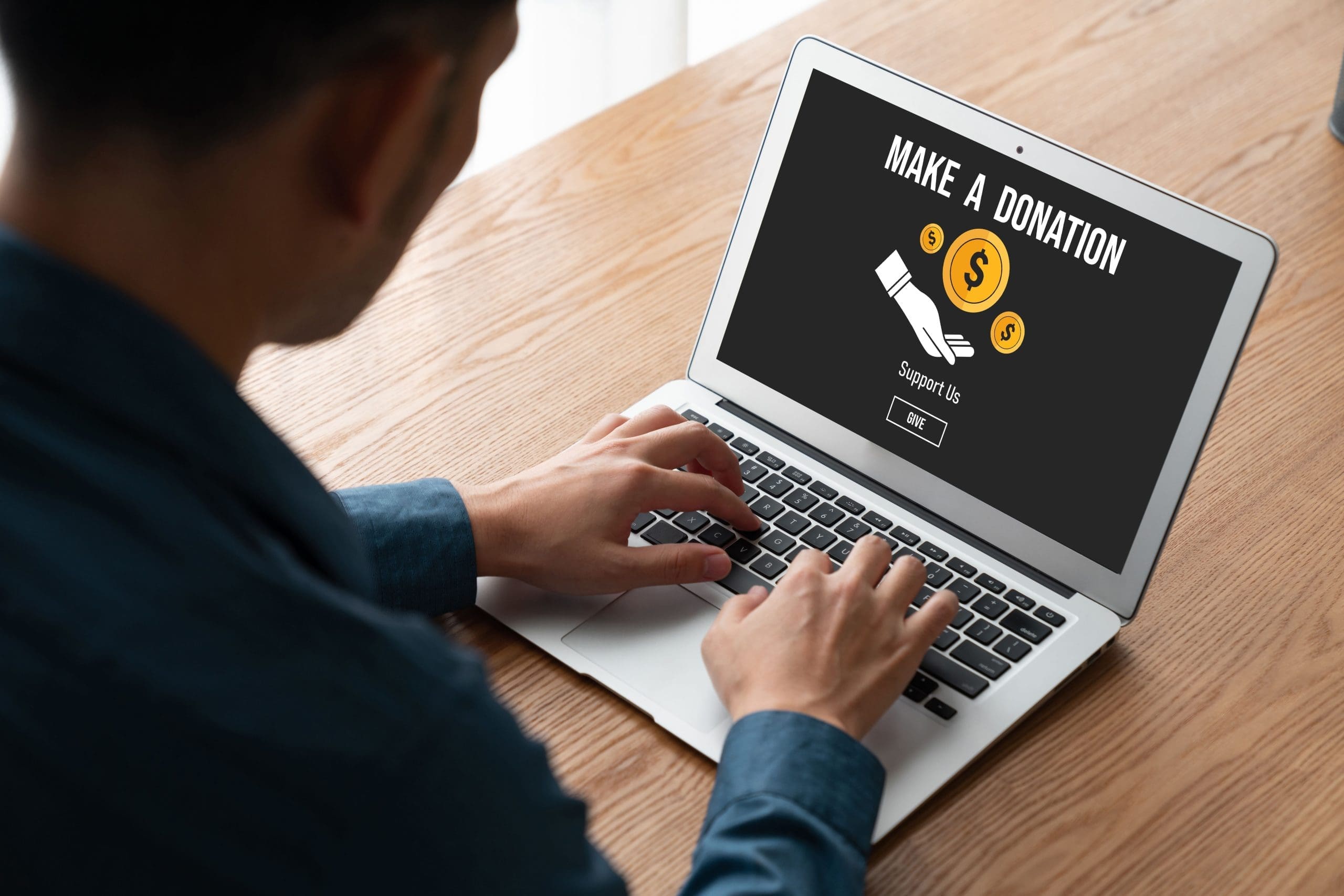 A man typing on a computer to access an Online donation platform