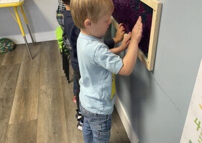 Three children playing with a sensory wall at Living Spring Church